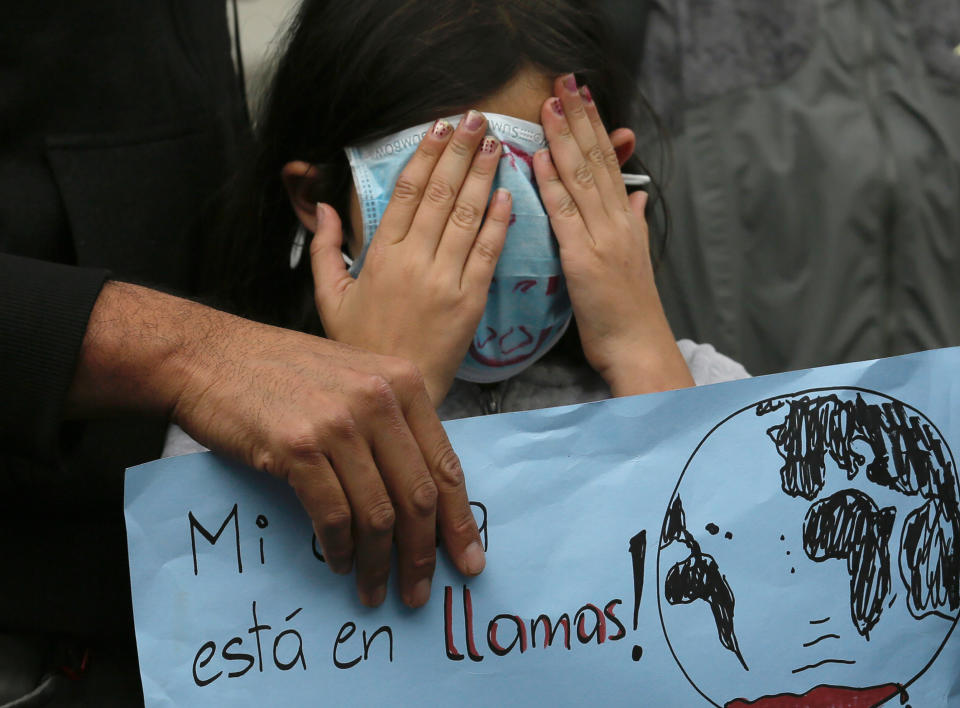 A girl covers her face during a global protest on climate change in front of government palaces, in Quito, Ecuador, Friday, Sept. 20, 2019. Across the globe, hundreds of thousands of people took to the streets to demand that leaders tackle climate change in the run-up to a U.N. summit. (AP Photo/Dolores Ochoa)