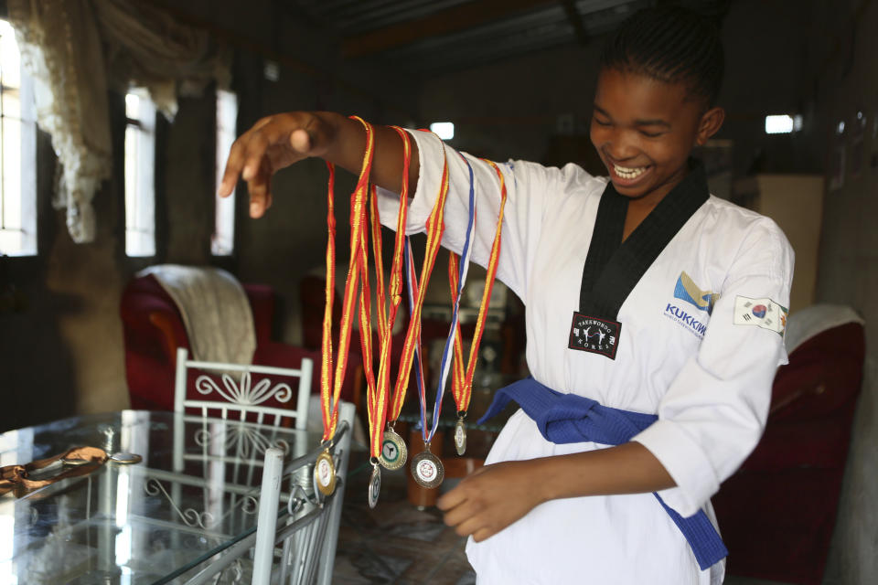 Natsiraishe Maritsa shows some of her taekwondo medals at her home in the Epworth settlement about 15 km southeast of the capital Harare, Saturday Nov. 7, 2020. In Zimbabwe, where girls as young as 10 are forced to marry due to poverty or traditional and religious practices, a teenage martial arts fan 17-year old Natsiraishe Maritsa is using the sport to give girls in an impoverished community a fighting chance at life. (AP Photo/Tsvangirayi Mukwazhi)
