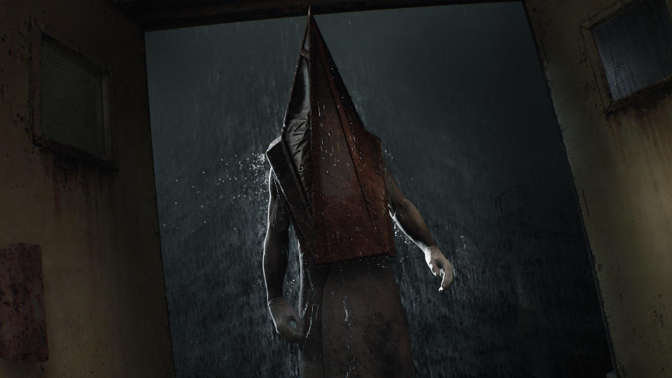 Pyramid Head stands in a dimly lit hallway