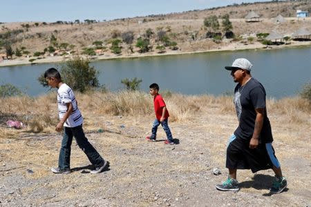 Arturo, 33, a Mexican migrant, who was denied a visa to the United States, walks with his sons Javen, 6 and Juan, 10, near a dam in Neutla, Guanajuato state, Mexico, April 9, 2019. Picture taken April 9, 2019. REUTERS/Edgard Garrido