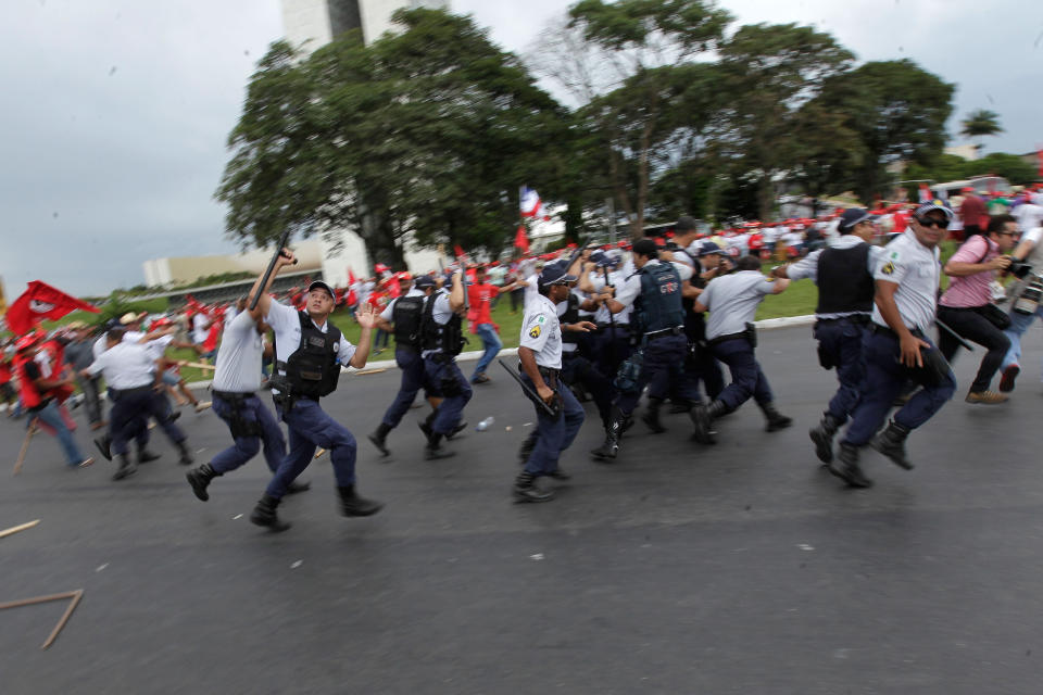 Brazilian riot police run away from missiles thrown at them by demonstrators during a march of The Landless Workers Movement, in front of the Planalto presidential palace, in Brasilia, Brazil, Wednesday, Feb. 12, 2014. The Landless Workers Movement, one of the globe’s biggest agrarian reform movements called the protest to demand that the government hand over more unused land to impoverished farmers who have none of their own. (AP Photo/Eraldo Peres)