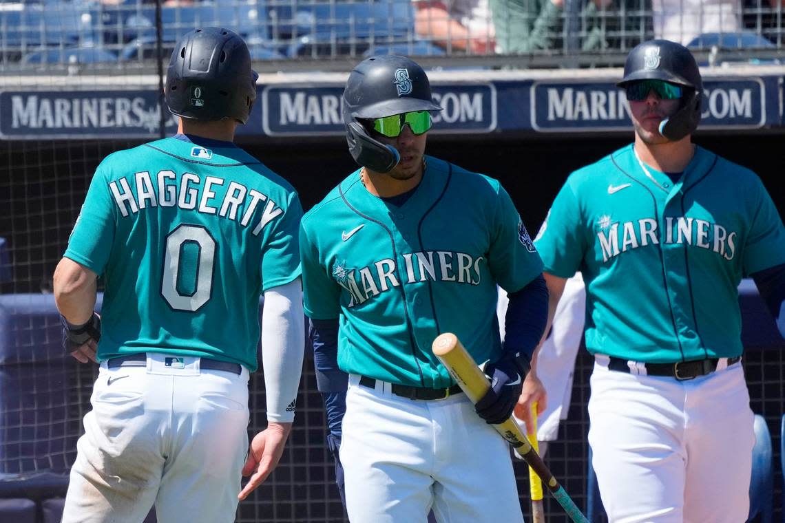 Seattle Mariners’ Sam Haggerty (0) celebrates after his run scored against the San Diego Padres with teammates Kolten Wong, center, and Ty France, right, during the third inning of a spring training baseball game Monday, March 27, 2023, in Peoria, Arizona.