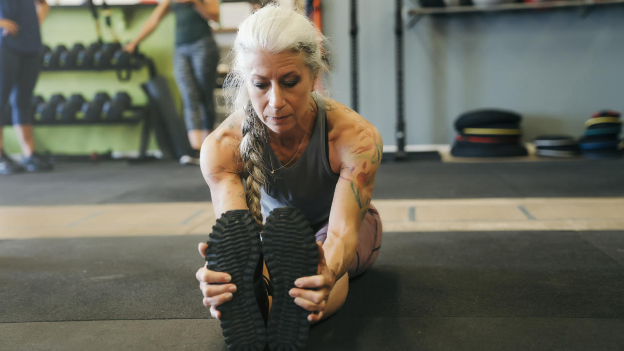  Mature woman stretching in the gym. 