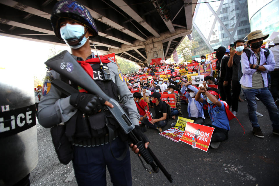 A policeman holding a long firearm stands in front of anti-coup protesters gathering outside the Hledan Centre in Yangon, Myanmar Friday, Feb. 19, 2021. The daily protests campaigning for civil disobedience in Myanmar are increasingly focusing on businesses and government institutions that sustain the economy. (AP Photo)