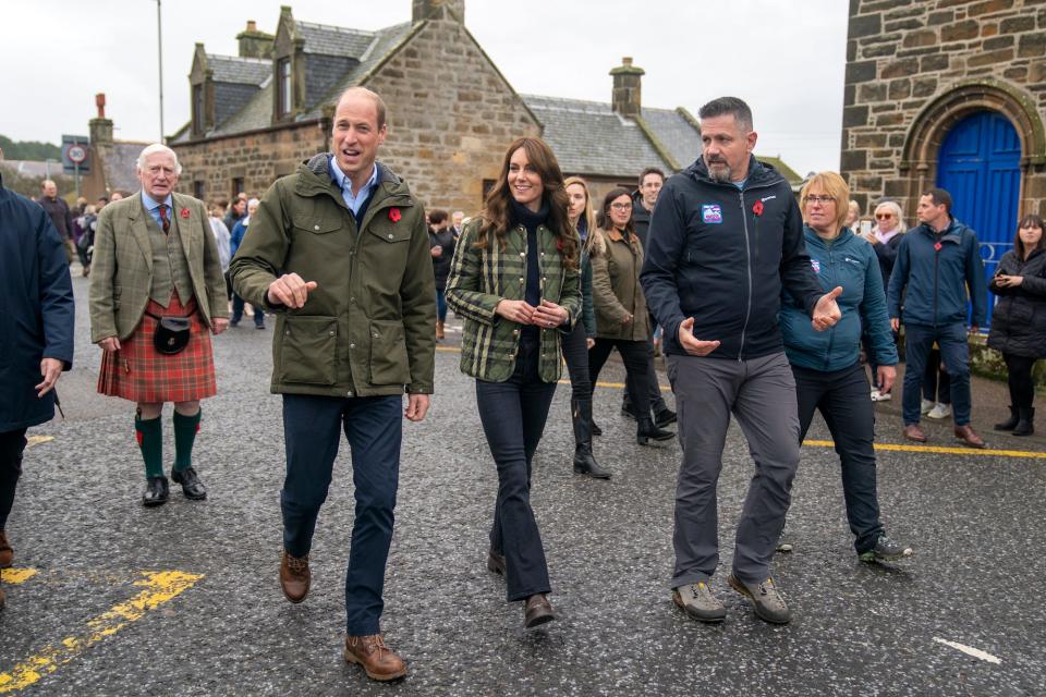 Prince William and Kate Middleton walk through the street with a crowd.