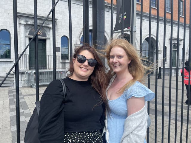 Two women stand in front of iron railings