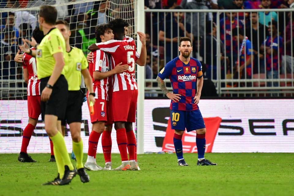 Barcelona's Lionel Messi (right) looks on as Atletico Madrid players celebrate Thursday's Spanish Super Cup semifinal win in Saudi Arabia. (Giuseppe Cacace/Getty)