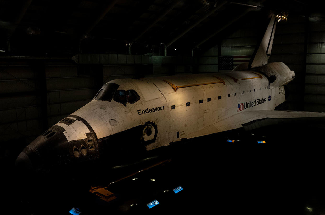  A space shuttle orbiter sits in a darkened hangar. 