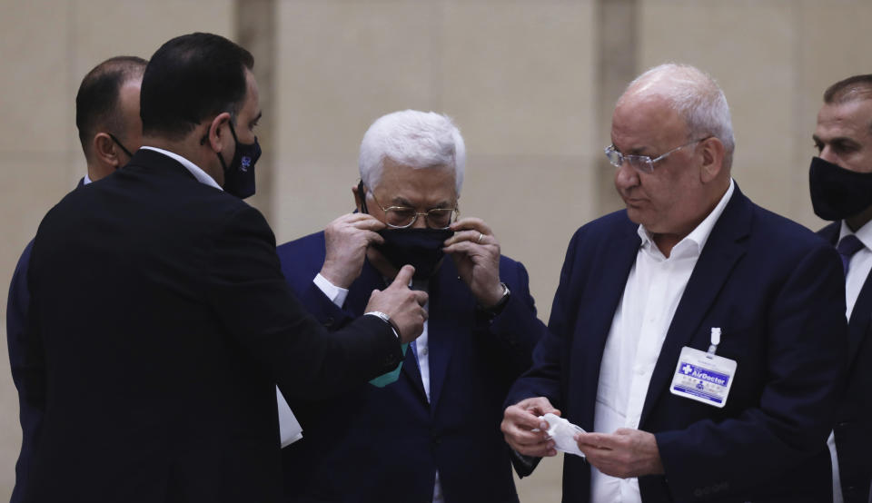 Palestinian President Mahmoud Abbas puts on a face mask as he heads a leadership meeting at his headquarters in the West Bank city of Ramallah on Tuesday, May 19, 2020. (Alaa Badarneh/Pool Photo via AP)