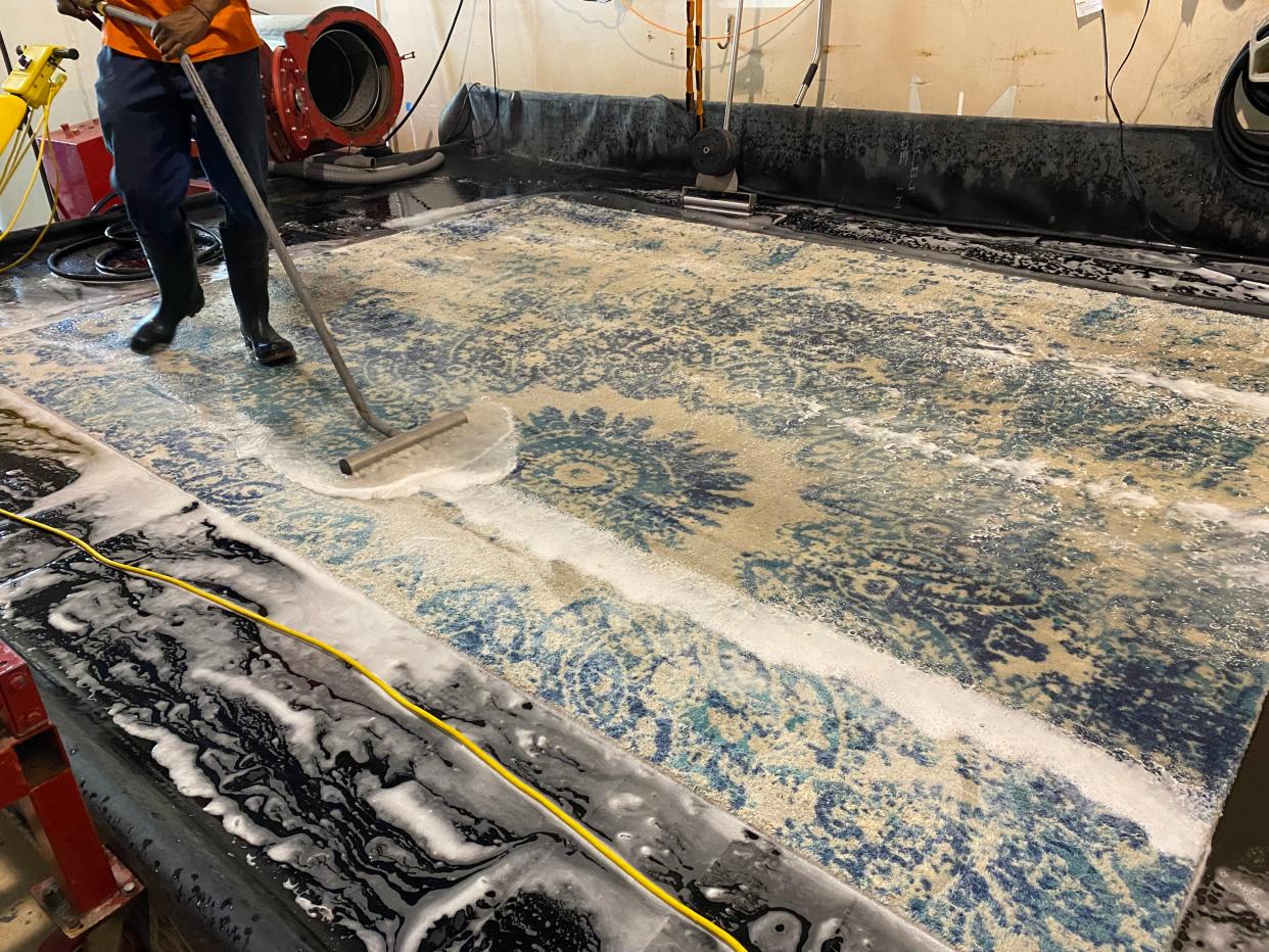 Washing area rugs properly is an art and a multistep process. After rugs are put in a tumbler to remove dry dust, they are washed and rinsed in a wash pit. Hanging the rug on a giant drying rack is the last step.