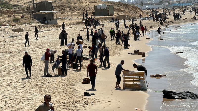 Palestinos en la playa recogiendo la ayuda lanzada por un avión, en medio del actual conflicto entre Israel y Hamás