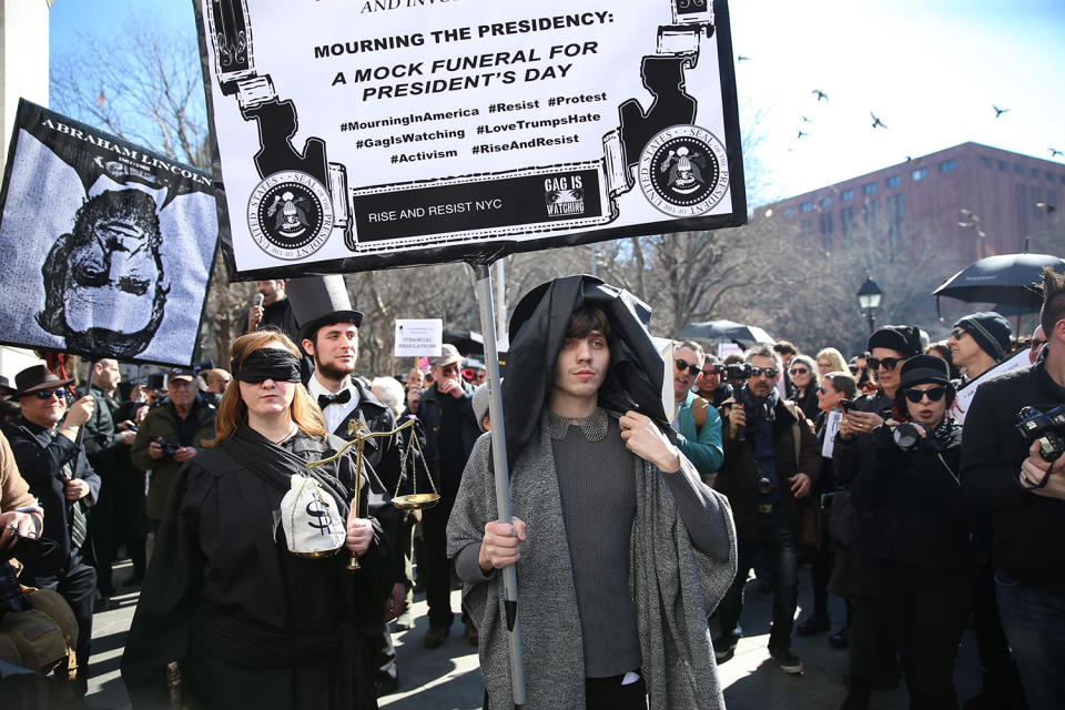 <p>Mourners walk in a procession carrying signs around Washington Square Park during the “Mock Funeral for Presidents’ Day” rally in New York City on Feb. 18, 2017. (Gordon Donovan/Yahoo News) </p>