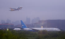 A Cebu Pacific passenger plane takes off, in background, while a Boeing passenger plane from China, a Xiamen Air, lies on the grassy portion of the runway of the Ninoy Aquino International Airport after it skidded off the runway while landing Friday, Aug. 17, 2018 in suburban Pasay city southeast of Manila, Philippines. All the passengers and crew of Xiamen Air flight MF8667 were safe and were taken to an airport terminal, where they were given blankets and food before being taken to a hotel. (AP Photo/Bullit Marquez)