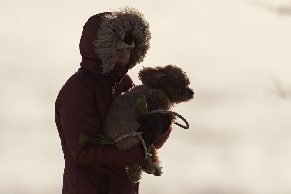 Una mujer carga a su perro en medio de un intenso frío en Portland, Maine, el sábado 4 de febrero de 2023. (AP Foto/Robert F. Bukaty)