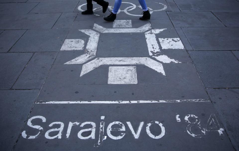 REFILE CORRECTING TYPO IN SARAJEVO People walk past the logo of the Winter Olympics in Sarajevo, painted on the streets in central Sarajevo October 27, 2013. Abandoned and left to crumble into oblivion, most of the 1984 Winter Olympic venues in Bosnia's capital Sarajevo have been reduced to rubble by neglect as much as the 1990s conflict that tore apart the former Yugoslavia. The bobsleigh and luge track at Mount Trebevic, the Mount Igman ski jumping course and accompanying objects are now decomposing into obscurity. The bobsleigh and luge track, which was also used for World Cup competitions after the Olympics, became a Bosnian-Serb artillery stronghold during the war and is nowadays a target of frequent vandalism. The clock is now ticking towards the 2014 Winter Olympics, with October 29 marking 100 days to the opening of the Games in the Russian city of Sochi. Picture taken on October 27, 2013. REUTERS/Dado Ruvic (BOSNIA AND HERZEGOVINA - Tags: SOCIETY SPORT OLYMPICS SKIING BUSINESS LOGO) ATTENTION EDITORS: PICTURE 23 OF 23 FOR PACKAGE 'SARAJEVO'S WINTER OLYMPIC LEGACY'. TO FIND ALL IMAGES SEARCH 'DADO IGMAN'