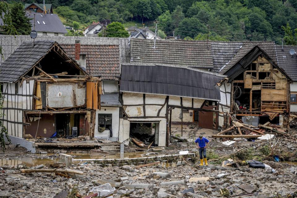 A man stands in front of destroyed houses in Schuld, Germany, Thursday, July 15, 2021. Due to heavy rain falls the Ahr river dramatically went over the banks the evening before. People have died and dozens of people are missing in Germany after heavy flooding turned streams and streets into raging torrents, sweeping away cars and causing some buildings to collapse. (AP Photo/Michael Probst)