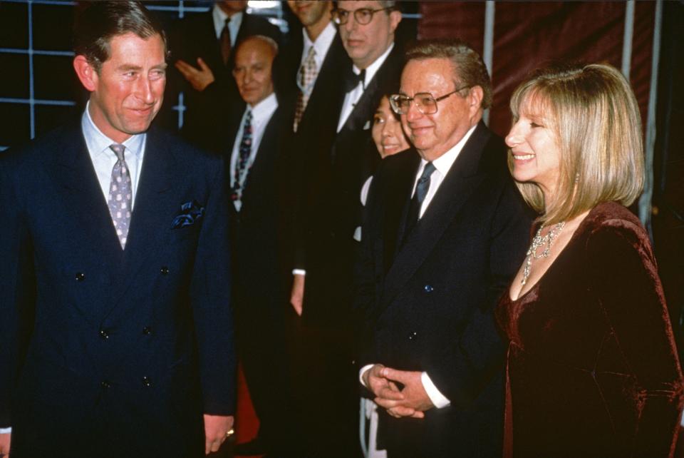 King Charles III, in a blue suit, smiles at Barbra Streisand, in a maroon velvet dress, while backstage at her London concert in 1994.