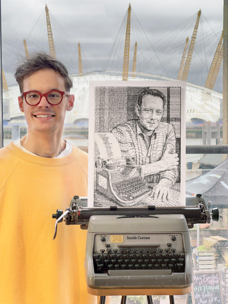 Man smiling and standing next to typewriter art 