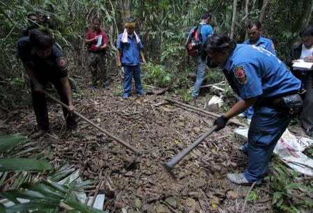 Security forces and rescue workers inspect a mass grave at a rubber plantation near a mountain in Thailand's southern Songkhla province May 7, 2015. REUTERS/Surapan Boonthanom