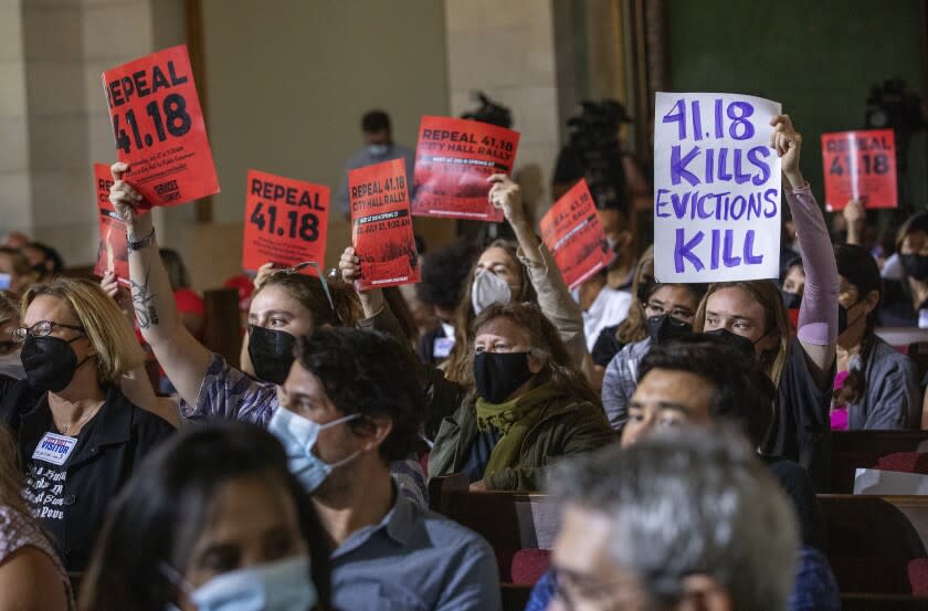 LOS ANGELES, CA-July 27, 2022:Joanna Swan, right, holds a sign showing that she is against a ban on homeless encampments near schools and daycare centers, while sitting with others also against the ban, inside Los Angeles City Hall, where members of the Los Angeles City Council were to vote on whether to approve or not approve the ban. The vote was postponed for 6 days. (Mel Melcon/Los Angeles Times)