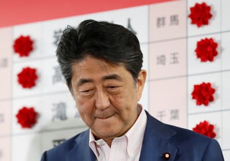 Japan's Prime Minister Shinzo Abe, who is also leader of the ruling Liberal Democratic Party (LDP), looks on as he puts a rosette on the name of a candidate who is expected to win the upper house election, at the LDP headquarters in Tokyo