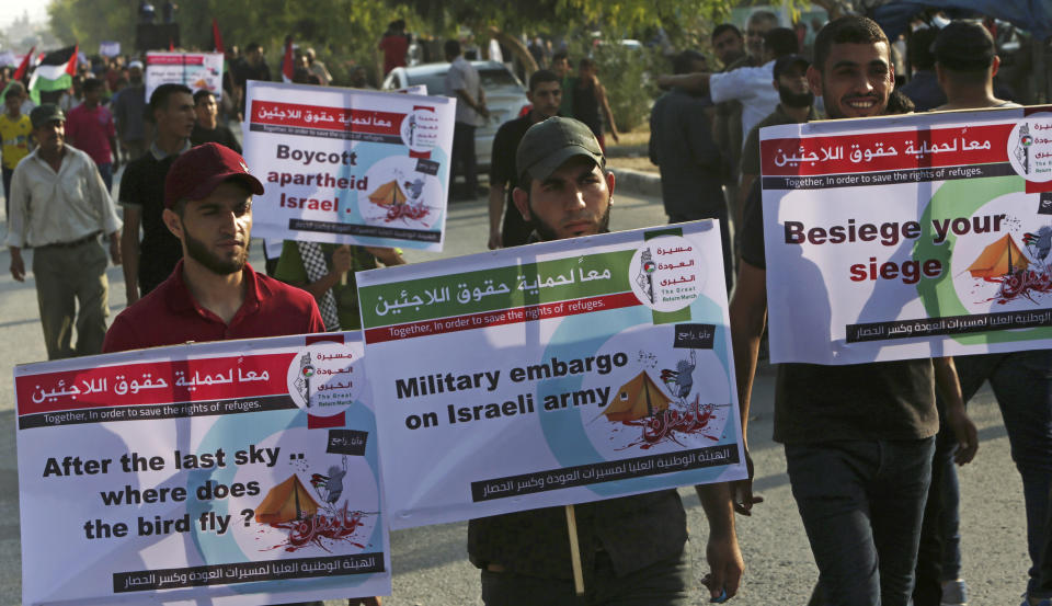 Demonstrators hold placards during a protest at the Palestinians side of Erez border crossing between Gaza and Israel, in Beit Hanoun, northern Gaza Strip, Tuesday, Sept. 4, 2018. The Health Ministry in Gaza says several Palestinians were wounded by Israeli fire as they protested near the territory's main personnel crossing with Israel. (AP Photo/Adel Hana)