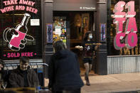 A member of bar staff wears a facemask at a bar in Manchester's Northern Quarter after Prime Minister Boris Johnson set out new restrictions to last "perhaps six months" to slow the renewed spread of coronavirus, Manchester, England, Tuesday Sept 22, 2020. The UK has reached "a perilous turning point", Boris Johnson said as he set out a raft of new coronavirus restrictions for England. ( AP Photo/Jon Super)