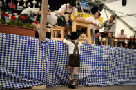 A young boy in traditional clothes watches a bout at the German Championships in Fingerhakeln or finger wrestling, in Bernbeuren, Germany, Sunday, May 12, 2024. Competitors battled for the title in this traditional rural sport where the winner has to pull his opponent over a marked line on the table. (AP Photo/Matthias Schrader)