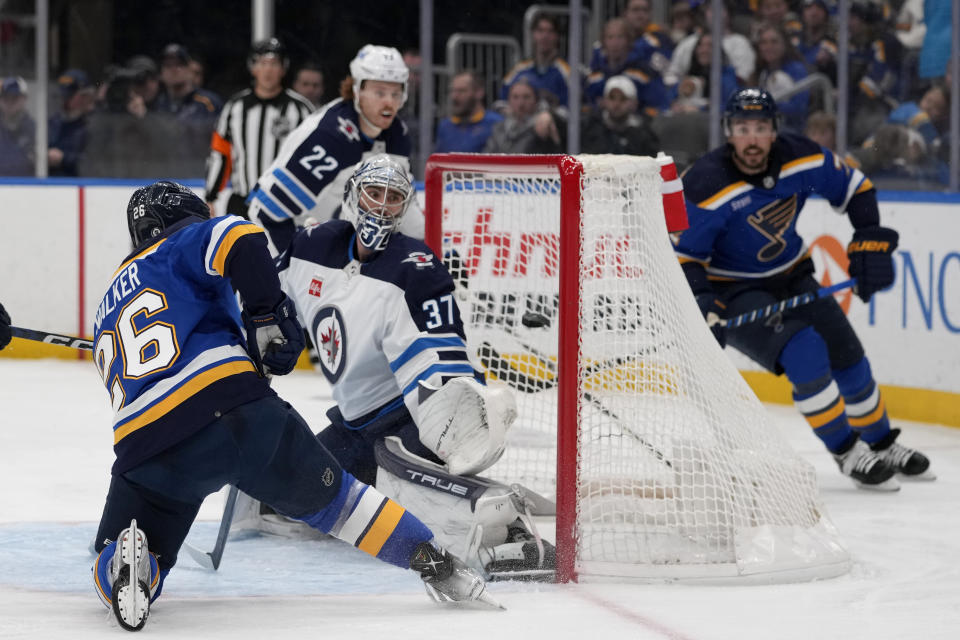 St. Louis Blues' Nathan Walker (26) scores past Winnipeg Jets goaltender Connor Hellebuyck (37) during the second period of an NHL hockey game Sunday, March 19, 2023, in St. Louis. (AP Photo/Jeff Roberson)