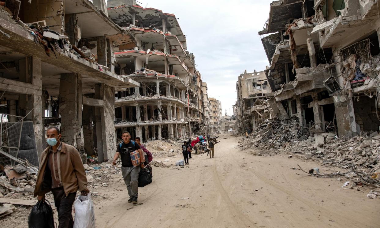<span>Palestinians walk with their belongings past destroyed buildings in Khan Younis on 8 April.</span><span>Photograph: Haitham Imad/EPA</span>