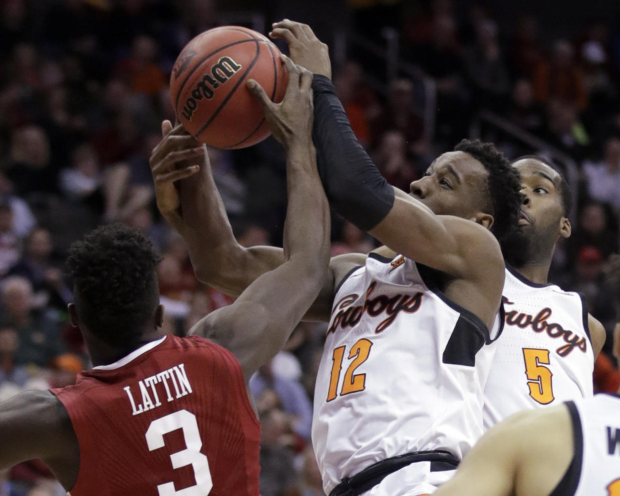 Oklahoma State forward Cameron McGriff (12) and Oklahoma forward Khadeem Lattin (3) reach for a rebound during the second half of an NCAA college basketball game in first round of the Big 12 men’s tournament in Kansas City, Mo., Wednesday, March 7, 2018. Oklahoma State defeated Oklahoma 71-60. (AP Photo/Orlin Wagner)