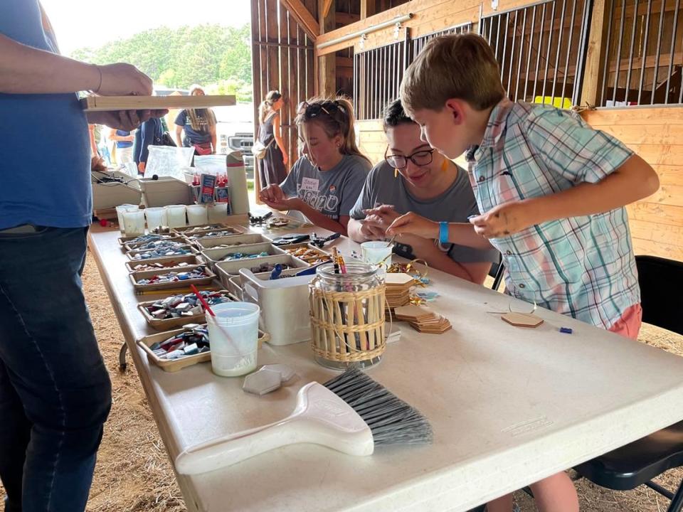 Ben Winkler, 8, consults with a Kidzu volunteer while crafting a mosaic from small tile chips at one of the educational stations for Kidzu’s June 2 Summerfest, held to show off its future N.C. Children’s Museum site on Mt. Carmel Church Road in Chapel Hill.