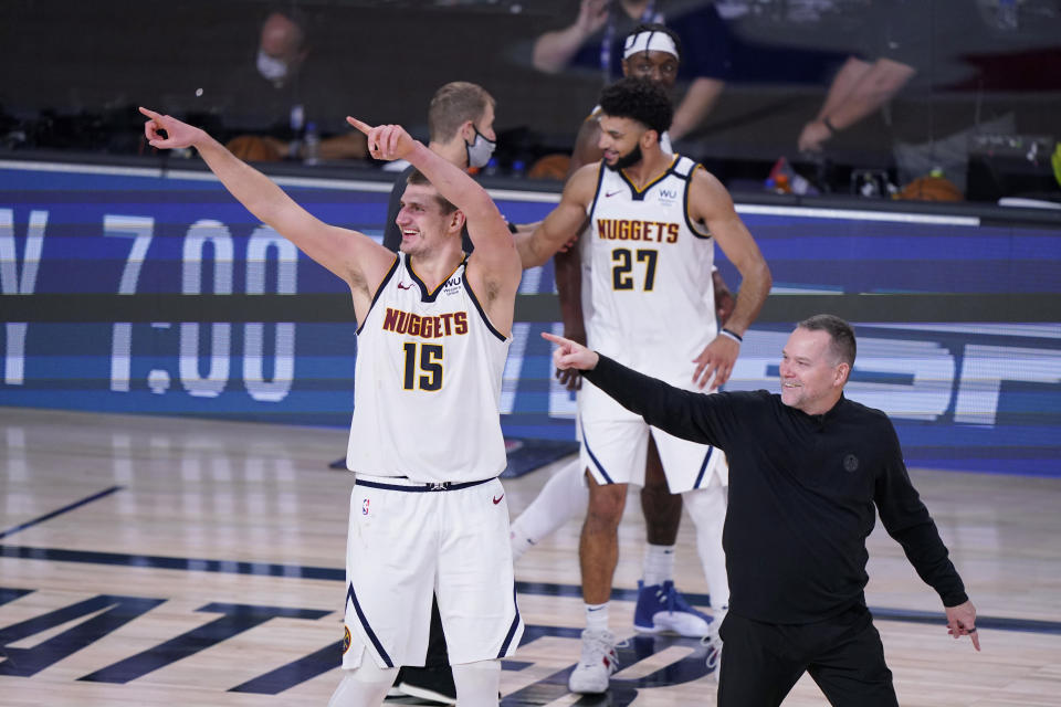 Denver Nuggets center Nikola Jokic (15) and Denver Nuggets head coach Michael Malone, right, celebrate their win over the Los Angeles Clippers in an NBA conference semifinal playoff basketball game Tuesday, Sept. 15, 2020, in Lake Buena Vista, Fla. (AP Photo/Mark J. Terrill)