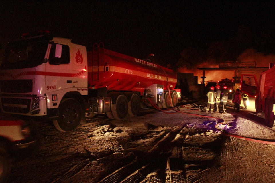 Iranian firefighters work on a burning tanker carrying fuel at the Islam Qala border with Iran, in Herat Province, west of Kabul, Afghanistan, Saturday, Feb. 13, 2021. The fuel tanker exploded Saturday at the Islam Qala crossing in Afghanistan's western Herat province on the Iranian border, injuring multiple people and causing the massive fire that consumed more than 500 trucks carrying natural gas and fuel, according to Afghan officials and Iranian state media. (AP Photo/Hamed Sarfarazi)