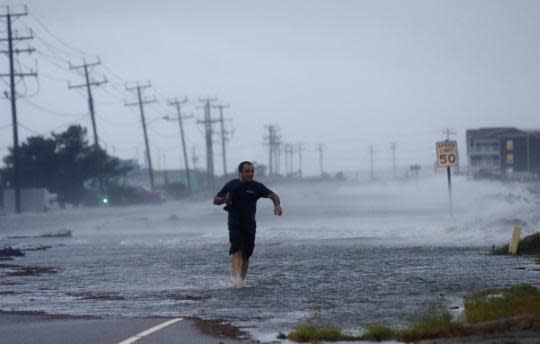 A man crosses a flooded Highway 64 as Hurricane Arthur passes through Nags Head, N.C., in 2014. (AP file)