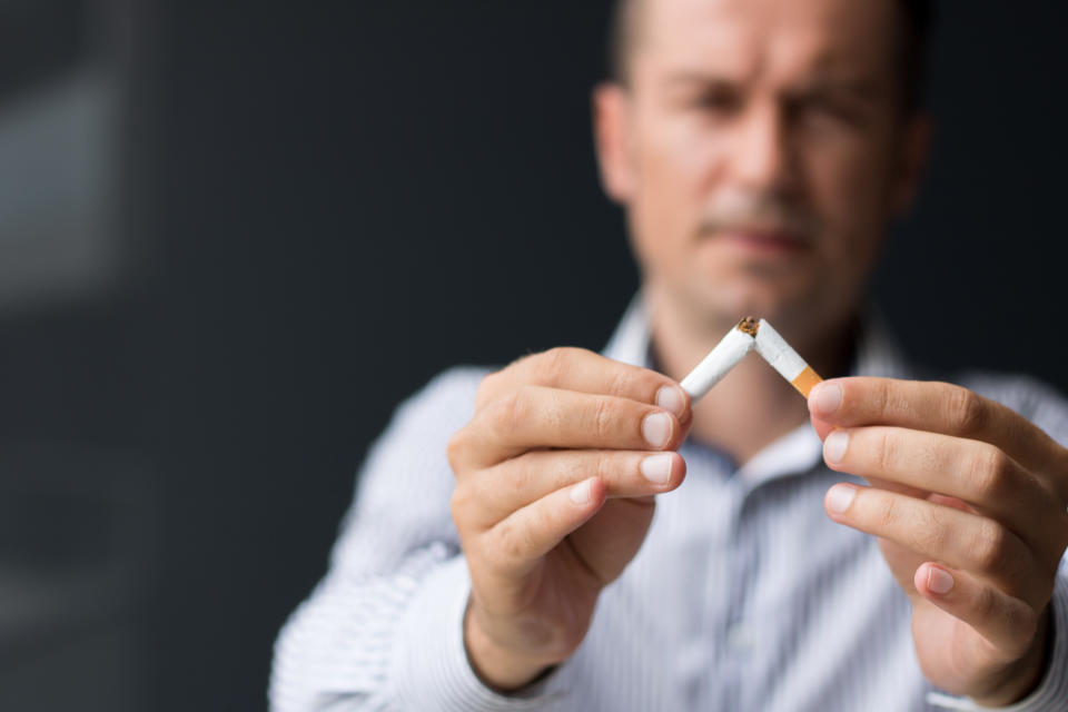 Close up of man breaking cigarette in half.  Quitting smoking habit.