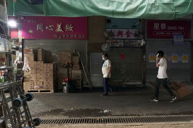 Men walk past shops catering to "parallel traders" in Sheung Shui