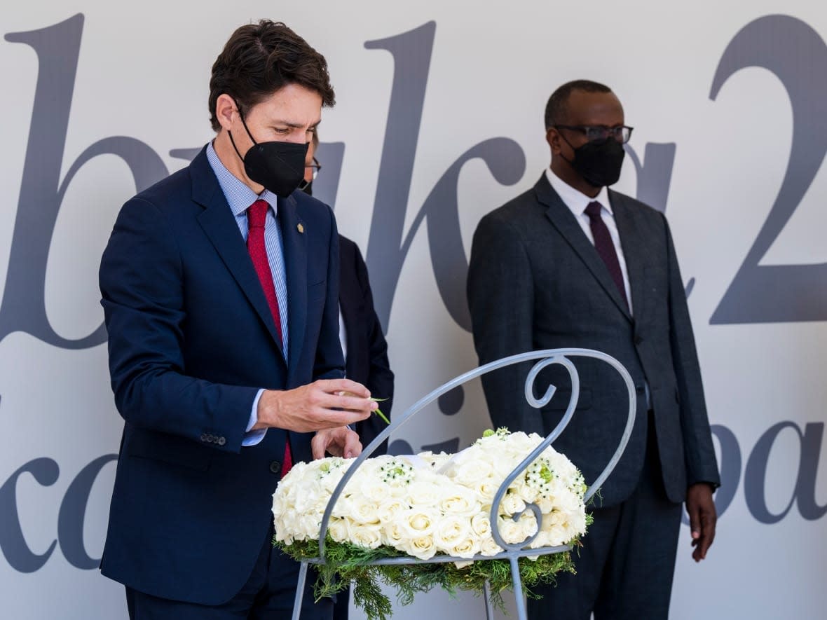 Prime Minister Justin Trudeau rearranges the flower on a wreath at the Kigali Genocide Memorial in Kigali, Rwanda, on Thursday. More than 250,000 victims of the genocide against the Tutsi have been buried in a mass grave at the memorial. (Paul Chiasson/The Canadian Press - image credit)