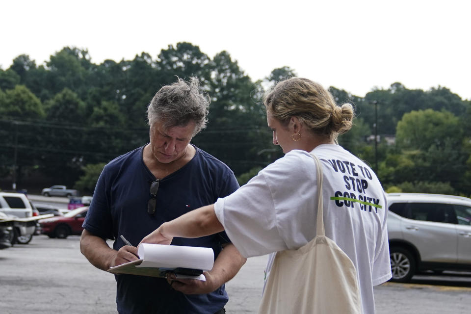Canvasser Sienna Giraldi, 26, right, talks to an Atlanta resident, left, Thursday, July 20, 2023, in Atlanta. Activists with the Stop Cop City Vote Coalition are trying to get the signatures of more than 70,000 Atlanta residents by Aug. 14 to force a referendum allowing voters to decide the fate of a proposed police and firefighter training center. (AP Photo/Brynn Anderson)