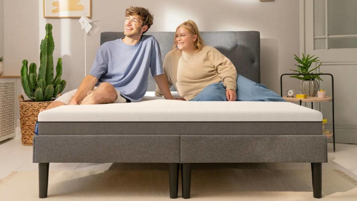  A man and a woman sitting on an Emma mattress. 