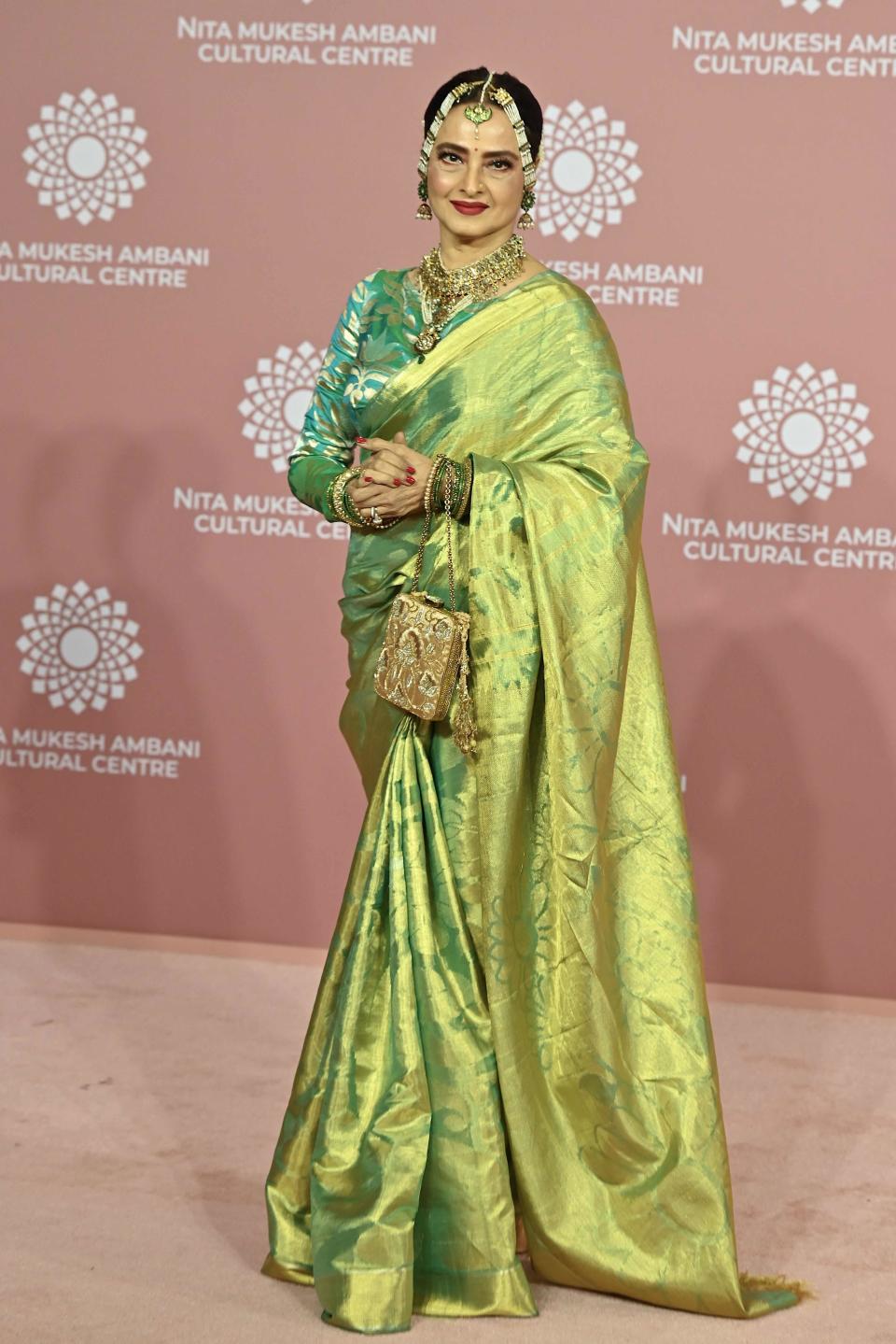 Bollywood actress Rekha radiates in a long-sleeved, yellow and green dress.