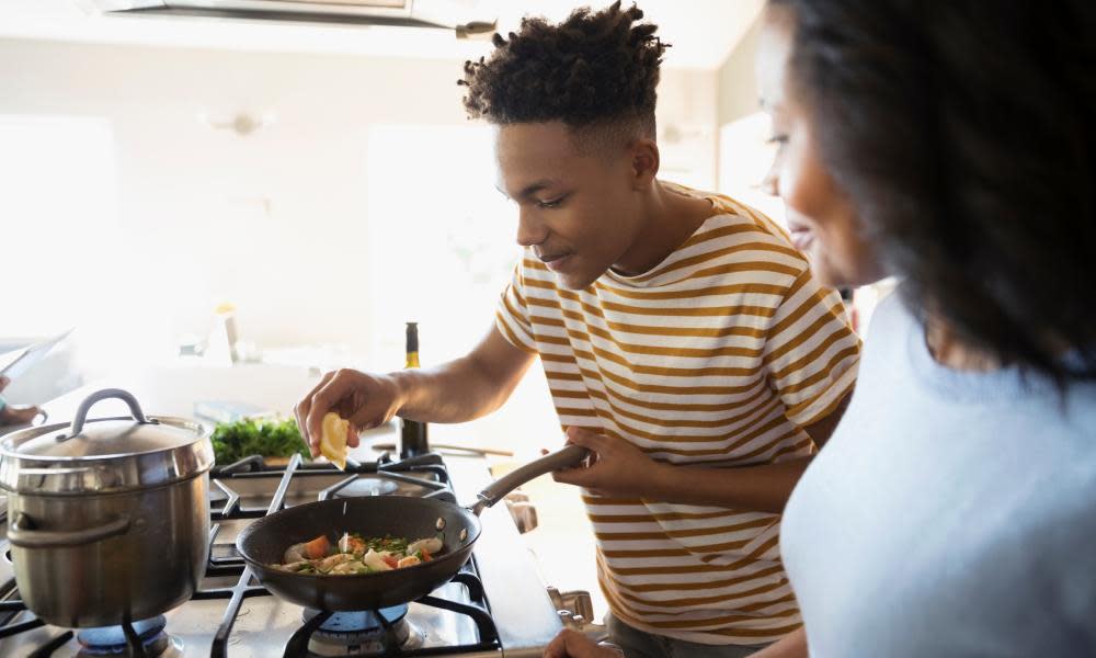 Mother and teenage son cooking at stove