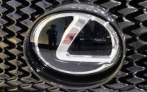 A security guard is reflected in the logo of a Toyota Motor Corp's Lexus car at the company's showroom in Tokyo May 31, 2013. REUTERS/Toru Hanai