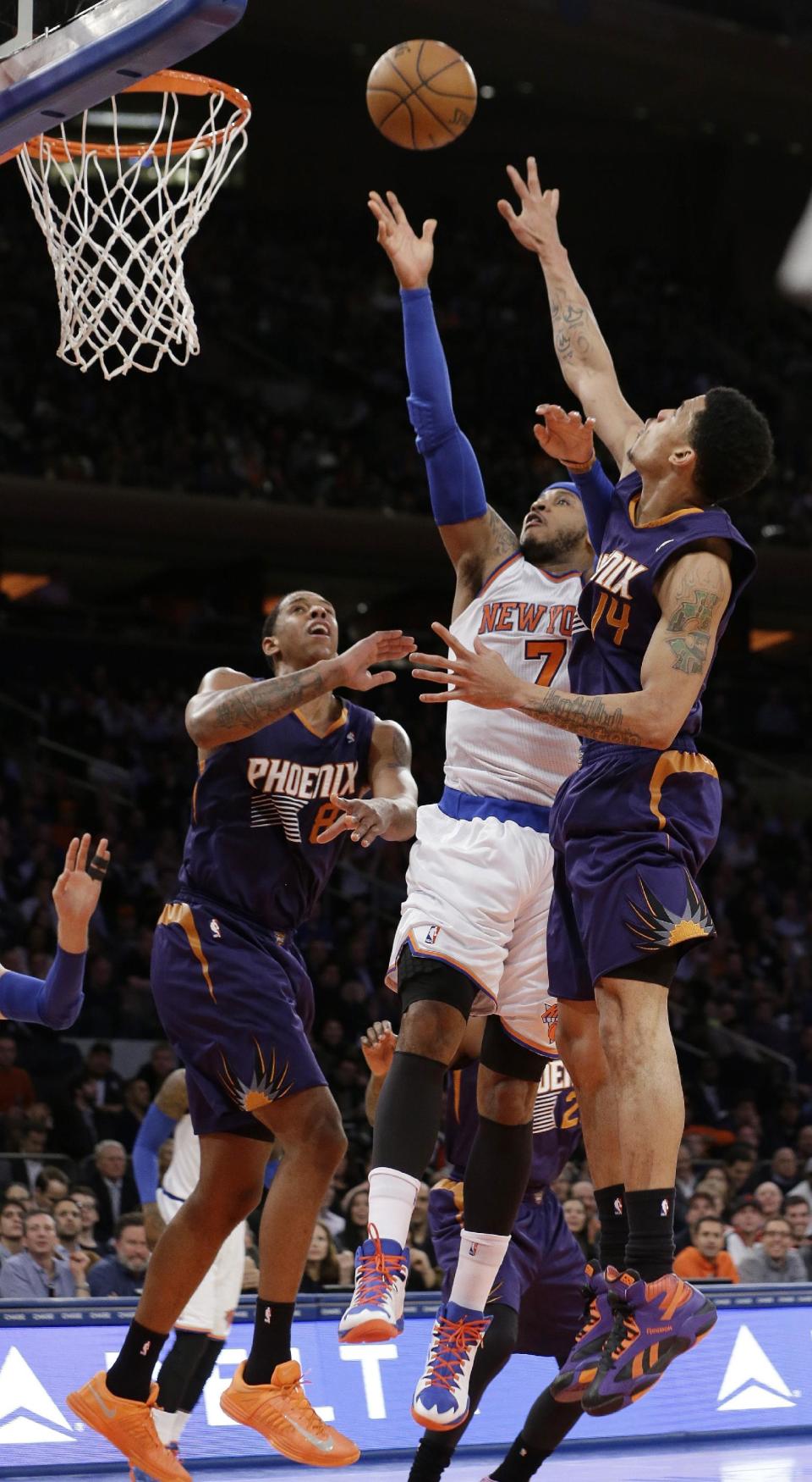 New York Knicks' Carmelo Anthony (7) drives past Phoenix Suns' Gerald Green (14) and Channing Frye (8) during the first half of an NBA basketball game, Monday, Jan. 13, 2014, in New York. (AP Photo/Frank Franklin II)