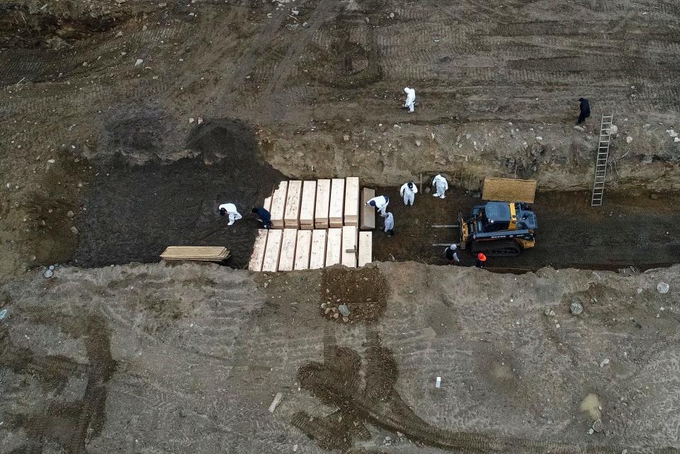 Workers wearing personal protective equipment bury bodies in a trench on Hart Island in the Bronx borough of New York. A disproportionate number of New York's coronavirus deaths have hit the city's Latino community.