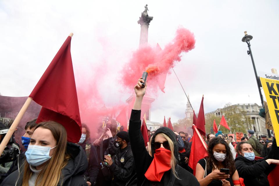 <p>A demonstrator releases coloured smoke during a 