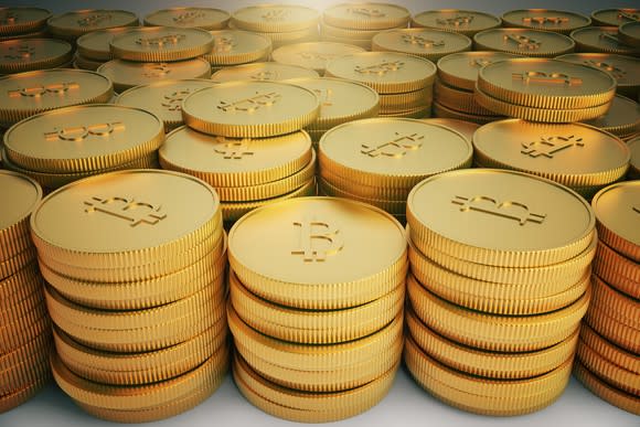 Stacks of gold coins with a bitcoin symbol on them.