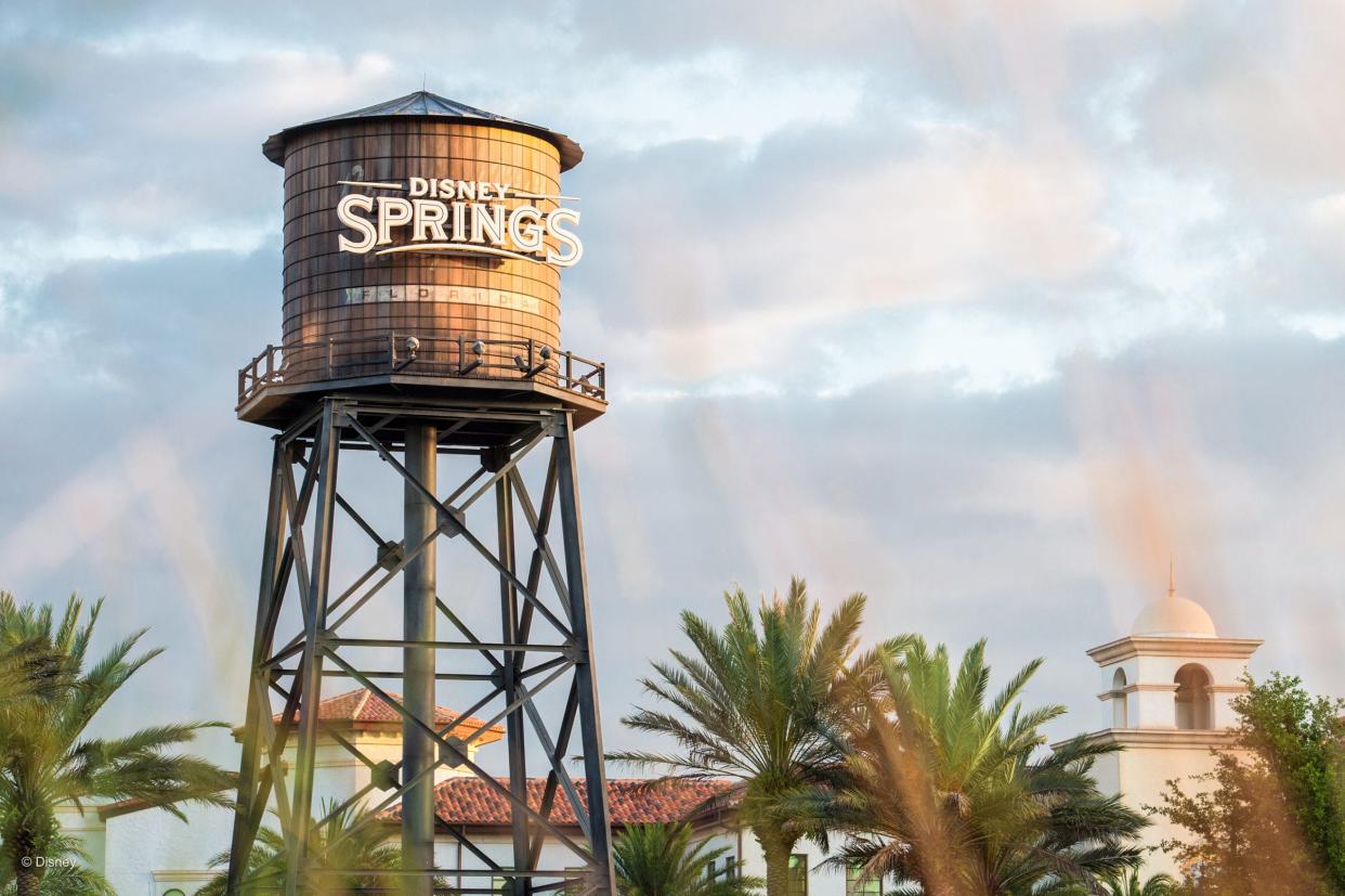 A photo of a sign on a water tower with the Disney Springs logo