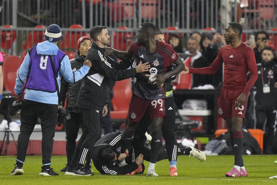 Toronto FC forward Prince Osei Owusu (99) is restrained by team staff members after the team's MLS soccer match against New York City FC on Saturday, May 11, 2024, in Toronto. (Frank Gunn/The Canadian Press via AP)