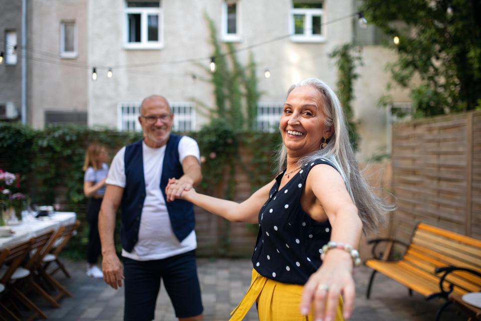 older couple dancing together in a backyard